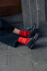 Person wearing black shoes and red socks sitting on a stone step.