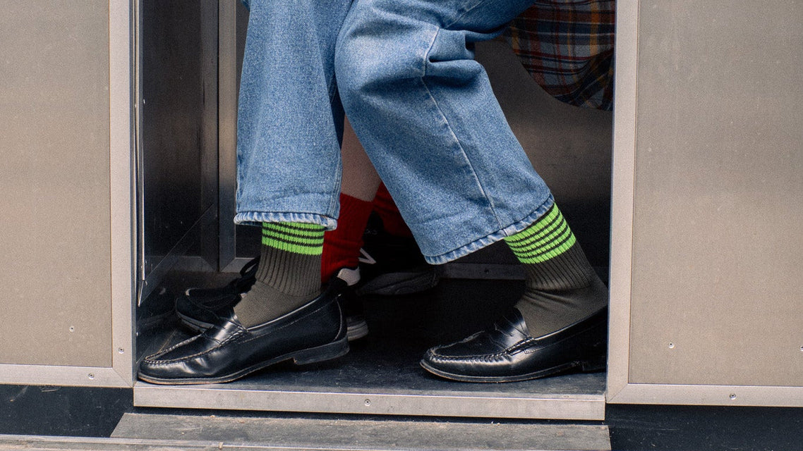 Person sitting inside a metal locker with another person partially visible in the reflection.