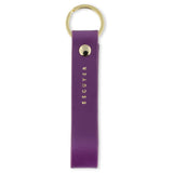 Escuyer violet leather keychain — Italian vegetable tanned leather tab with gold metal ring and gold Escuyer logo