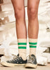Person wearing beige socks with green stripes and black sneakers on a blurred background
